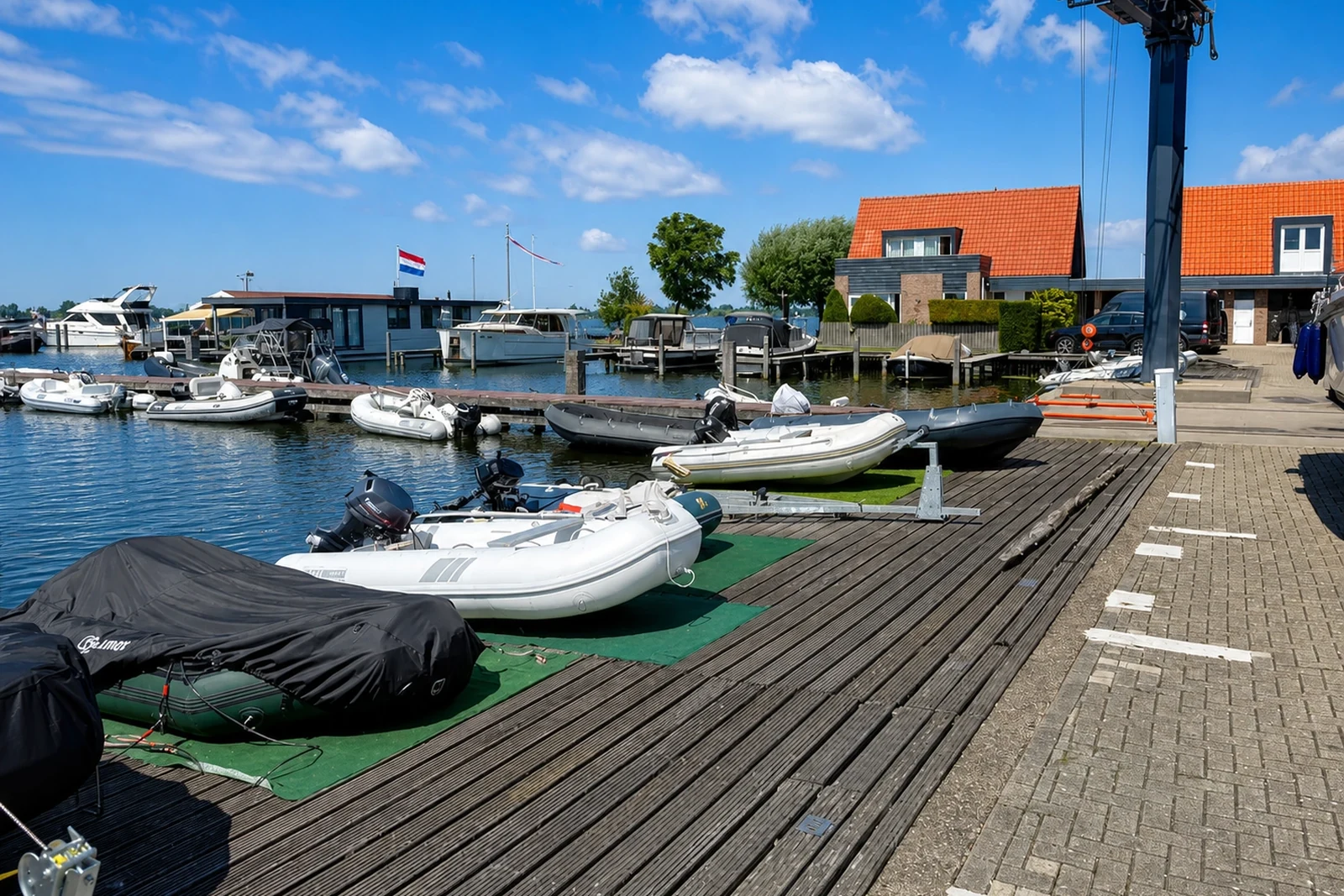 Botenkade met takelkraan en opgestelde vaartuigen aan het water