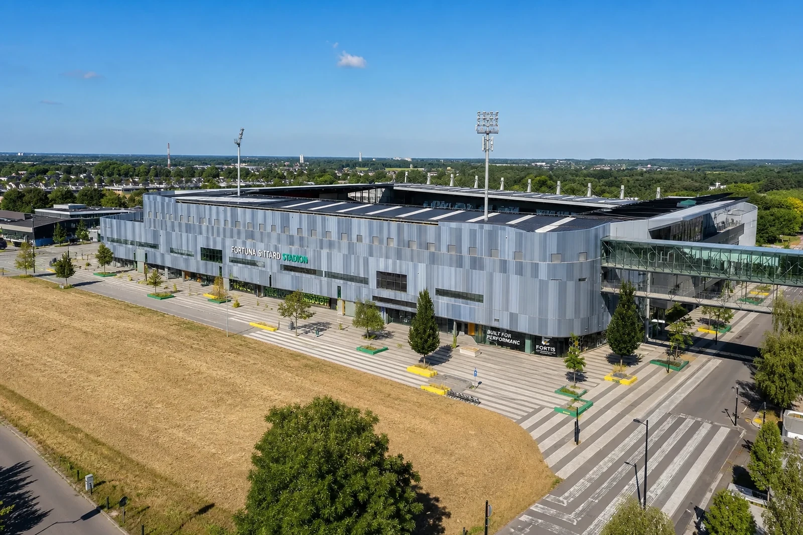 Groot parkeerterrein bij een stadion, gezien vanuit de lucht