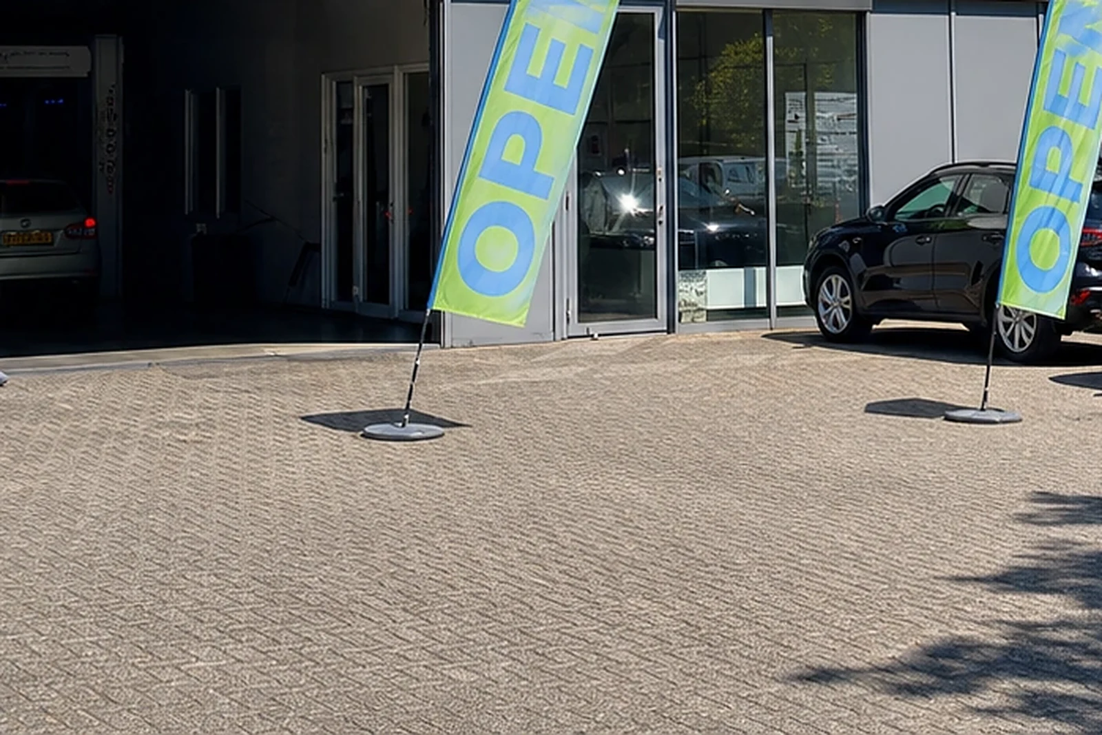 Ingang van een carwash met openstaande wasstraat en wachtende auto’s